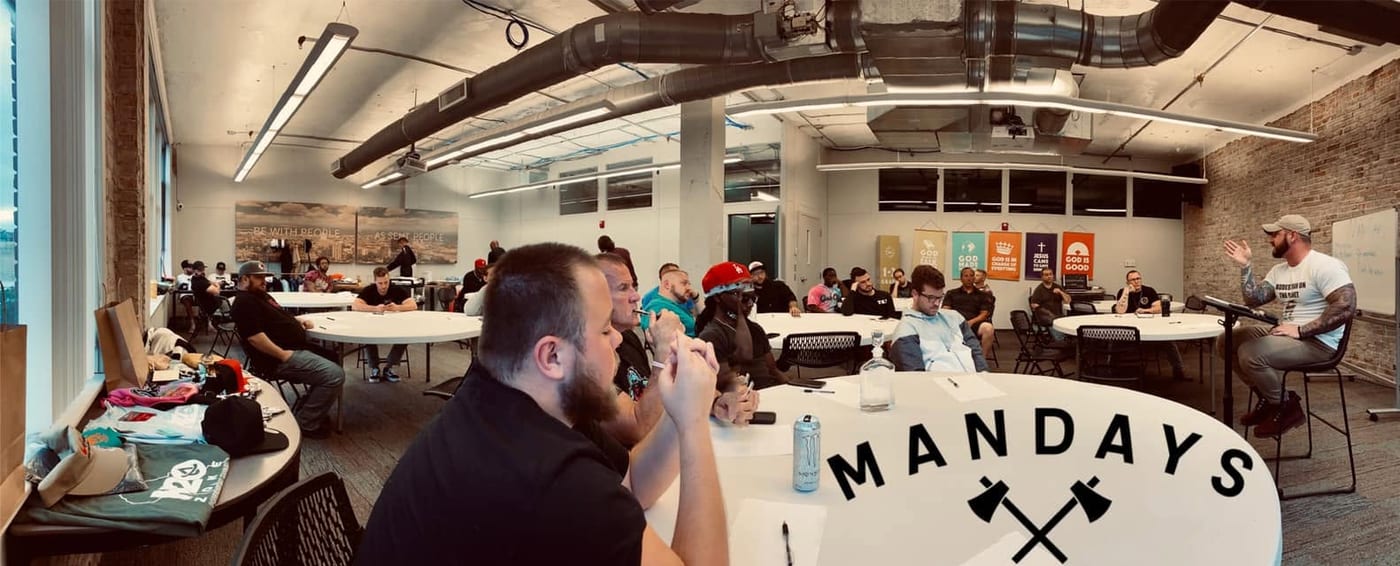 Panoramic view of a Man Days event — round tables, faith banners, and the MANDAYS logo
